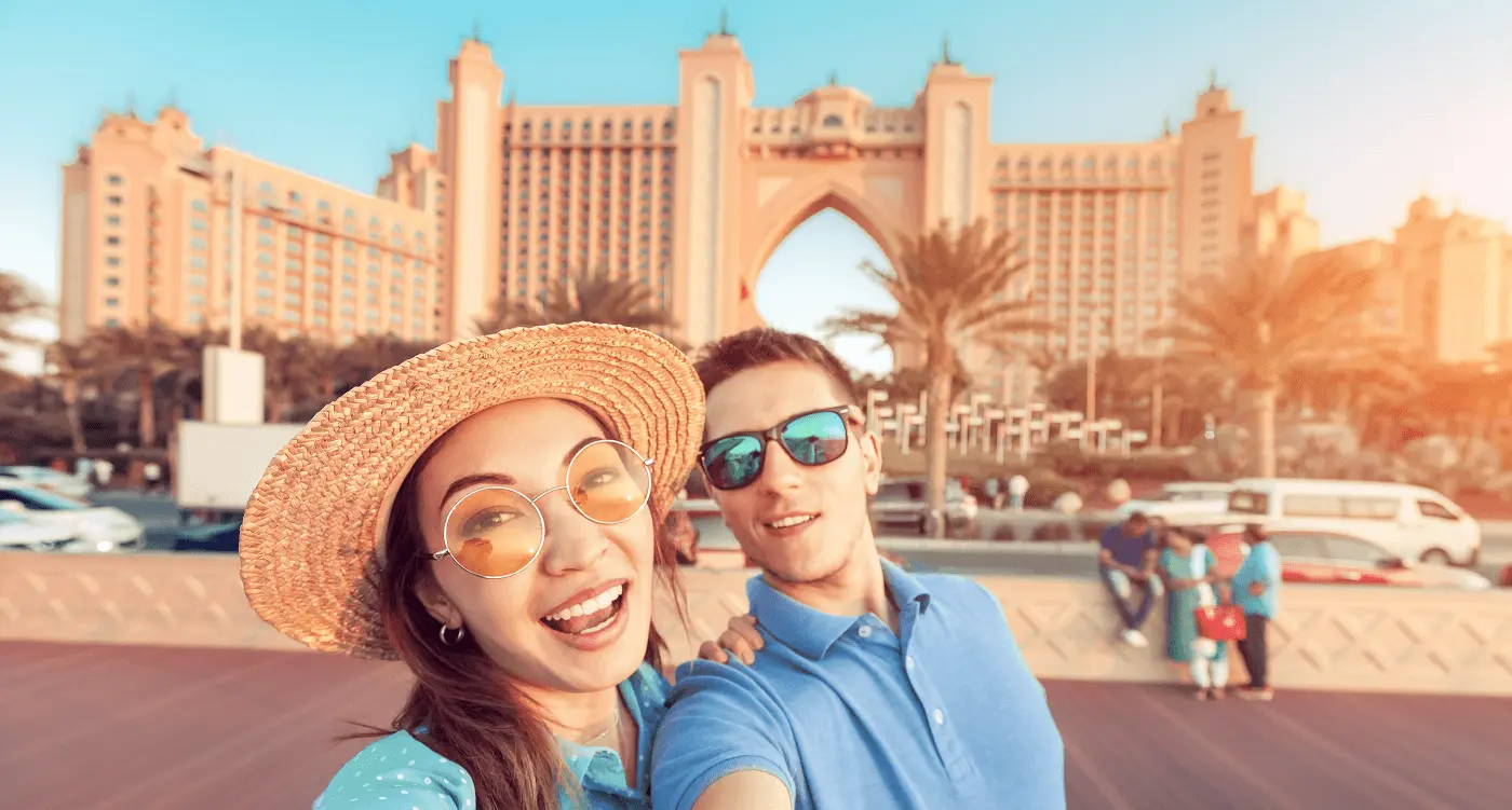 A couple taking a selfie with atlantis hotel behind them