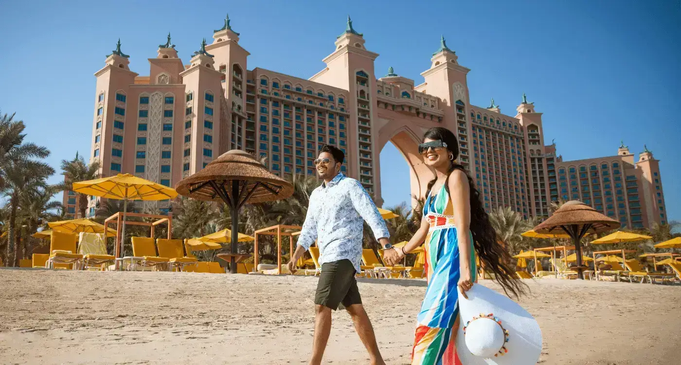 A couple walking on a beach in front of atlantis hotel the palm